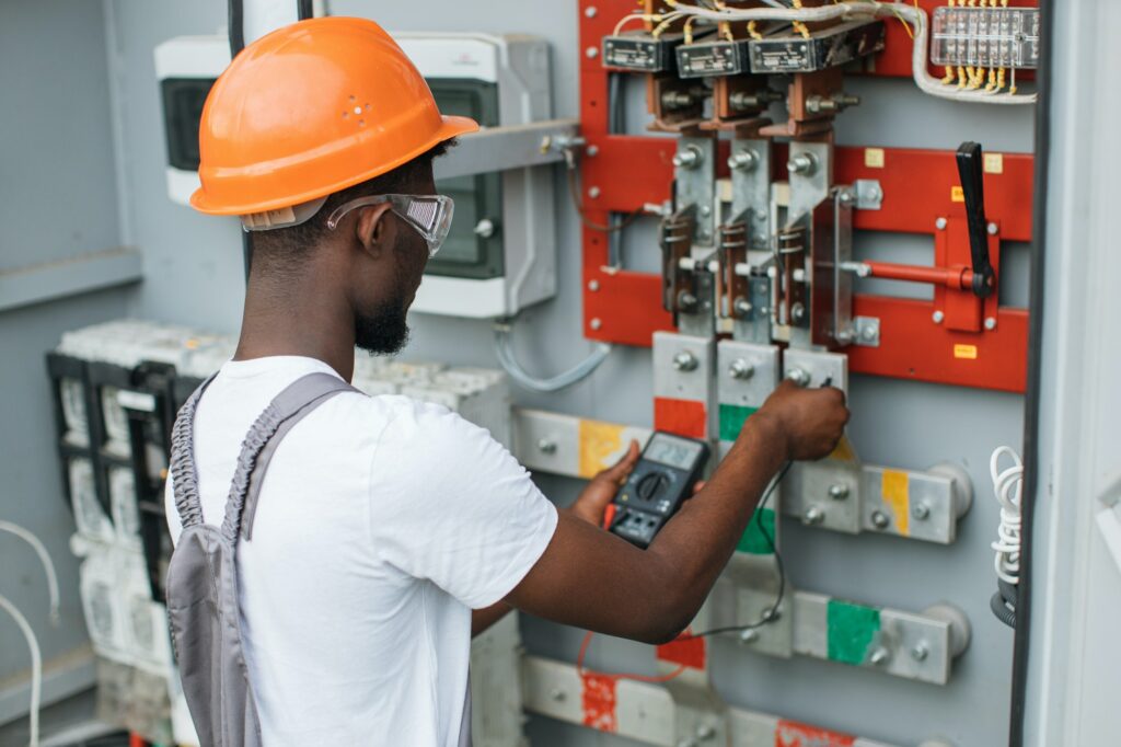 Electrician checking voltage in switchgear at solar station
