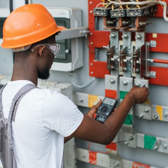 Electrician checking voltage in switchgear at solar station